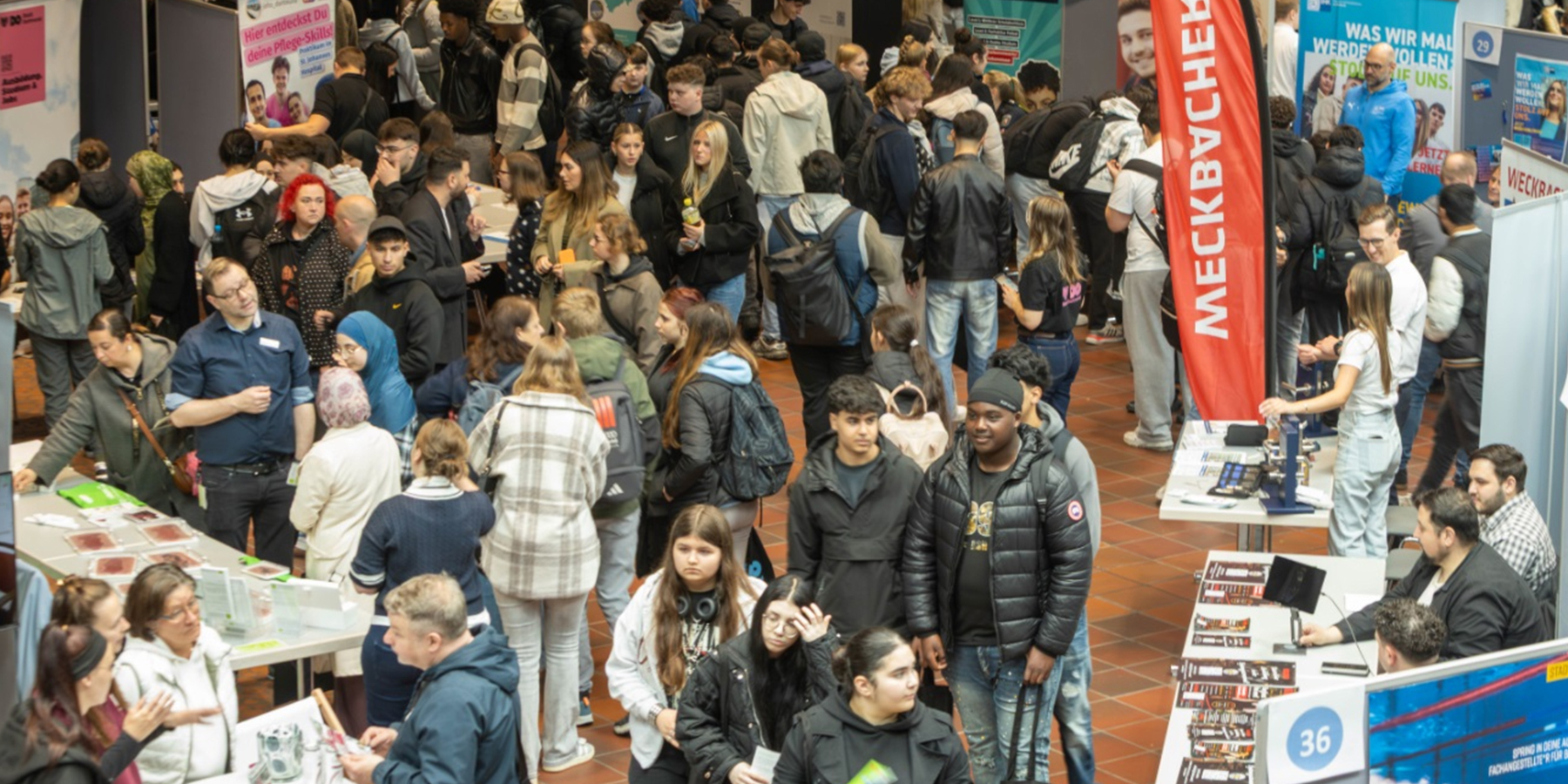 Schülerinnen und Schüler informieren sich auf der Ausbildungsmesse ‚Deine Zukunft – Nach der Schule!‘ an verschiedenen Messeständen.